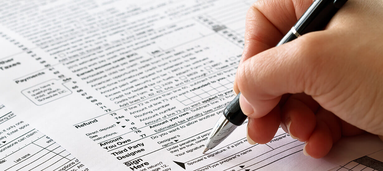 person filling out a paper tax return form